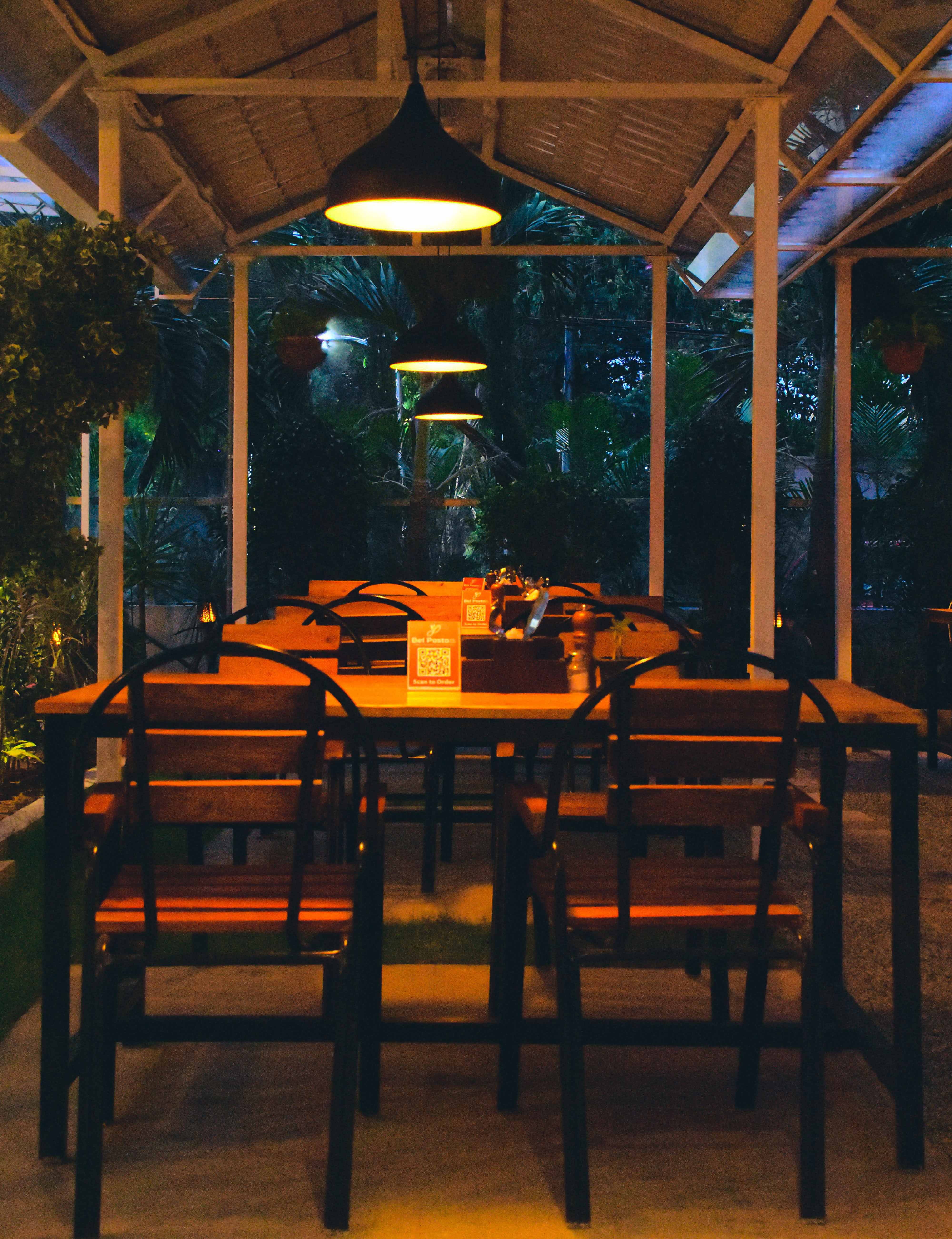Evening at Bel Posto The Cafe — garden tables under warm hanging lamps
